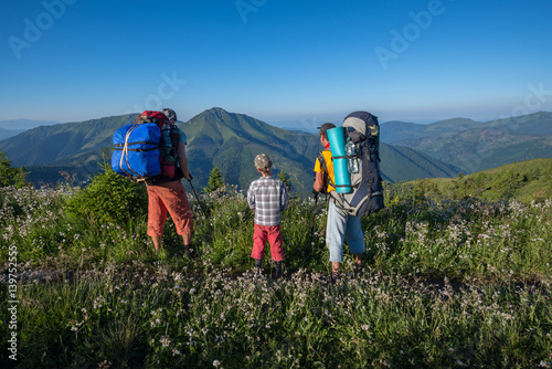 Happy travelers - men and boy relax on the alpine meadow