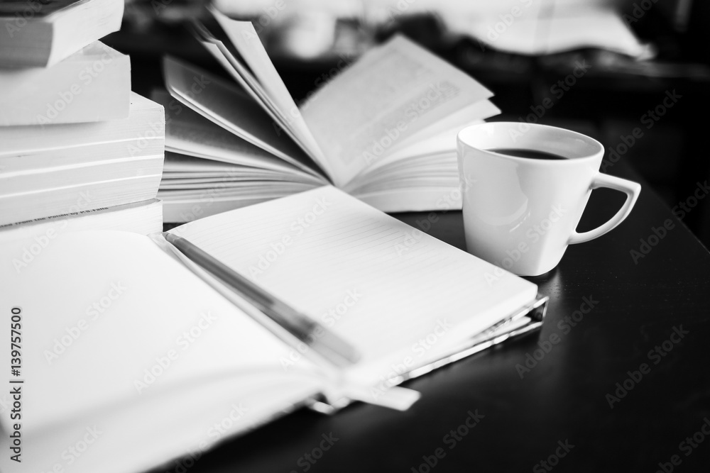 There are coffee, books, notebook and pen. Note-taking. Black and white photo There are coffee, books, notebook and pen. Note-taking. Black and white photo