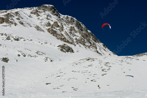 landscape of the Alps covered by snow and a skier who practice snowkite, leaving traces of the curves on the snow in a sunny day, Switzerland, Simplon Pass
