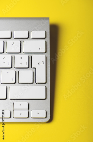 Part of a computer of a keyboard on a yellow background. Technology. Vertical shoot.