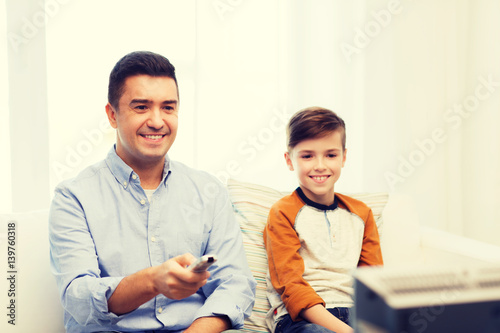 smiling father and son watching tv at home