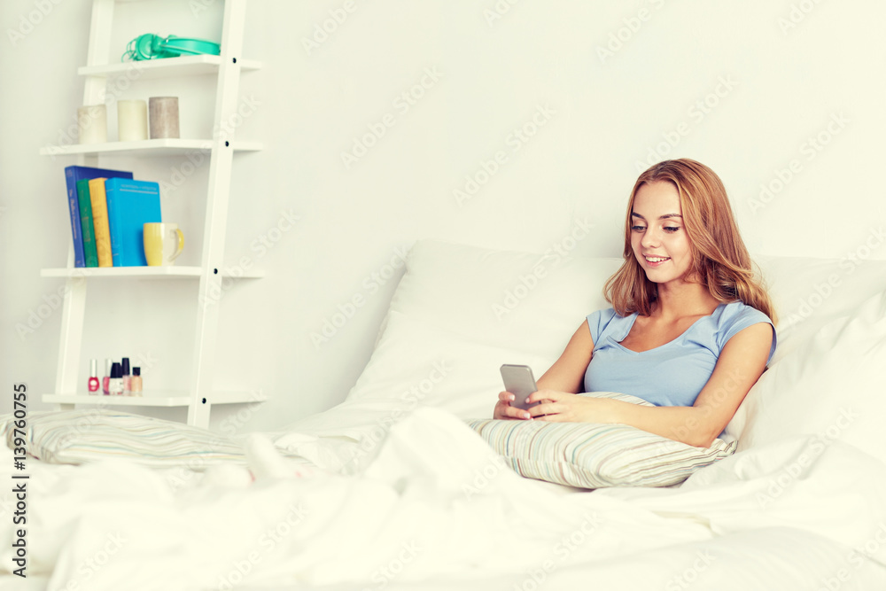 happy woman or girl with smartphone in bed at home happy woman or girl with smartphone in bed at home