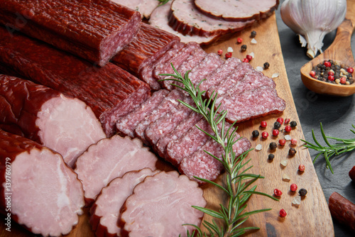 Foto Set of cold cuts on a wooden board. Mix of sausages