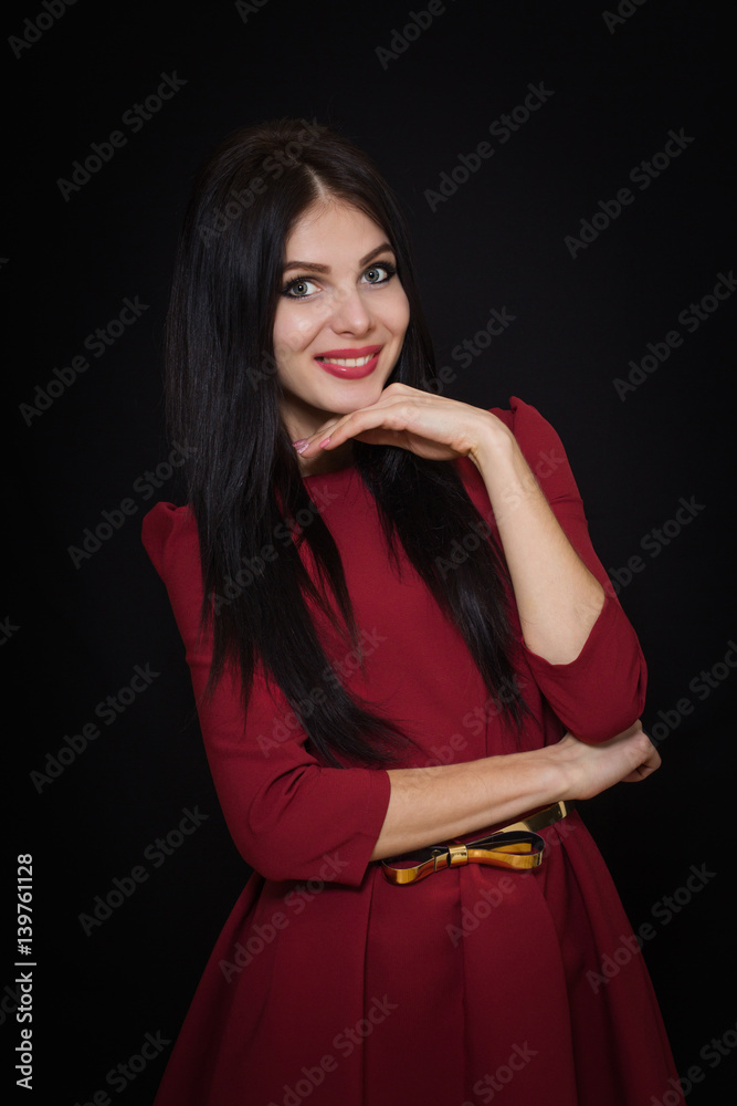 A beautiful woman with black straight hair and blue eyes in a burgundy dress on a dark background. Close-up. Space for text A beautiful woman with black straight hair and blue eyes in a burgundy dress on a dark background. Close-up. Space for text