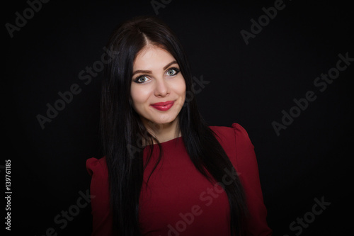 Beautiful woman with black straight hair and blue eyes on a dark background smiling. Close-up. Space for text