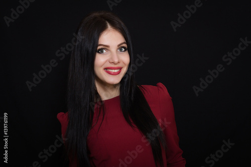 Beautiful woman with black straight hair and blue eyes on a dark background smiling. Close-up. Space for text