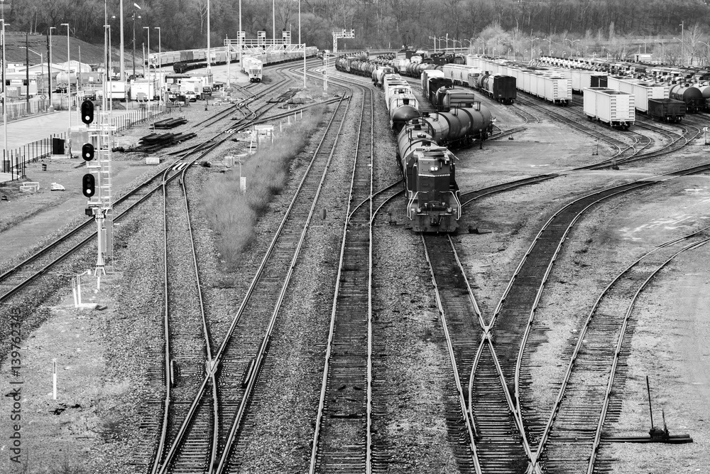 Busy trainyard with many trains on multiple switching tracks in black and white