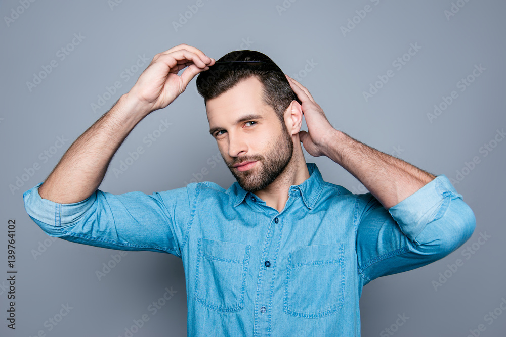 A portrait of a handsome confident man in jeans shirt combing his hair A portrait of a handsome confident man in jeans shirt combing his hair