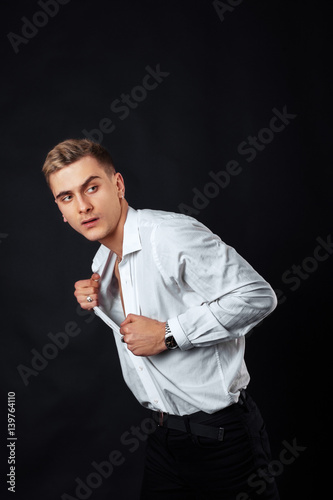 A young man in a white shirt on a black background. The concept of lifestyle, fashion