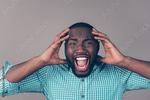 Portrait of furious afroamerican man in rage touching head and screaming