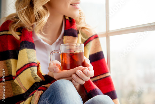 Close up photo cheerful happy woman holding cup of tea and sitting on windowsill. photo
