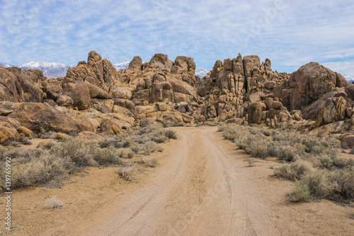 Dirt road leads toward boulder hills in California's Mojave Desert in Owen's Valley.