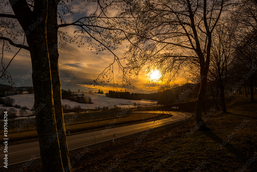 Geschwungene Straße ländliche winterliche Landschaft in Bayern mit schneebedeckten Hügeln. Geschwungene Straße ländliche winterliche Landschaft in Bayern mit schneebedeckten Hügeln.