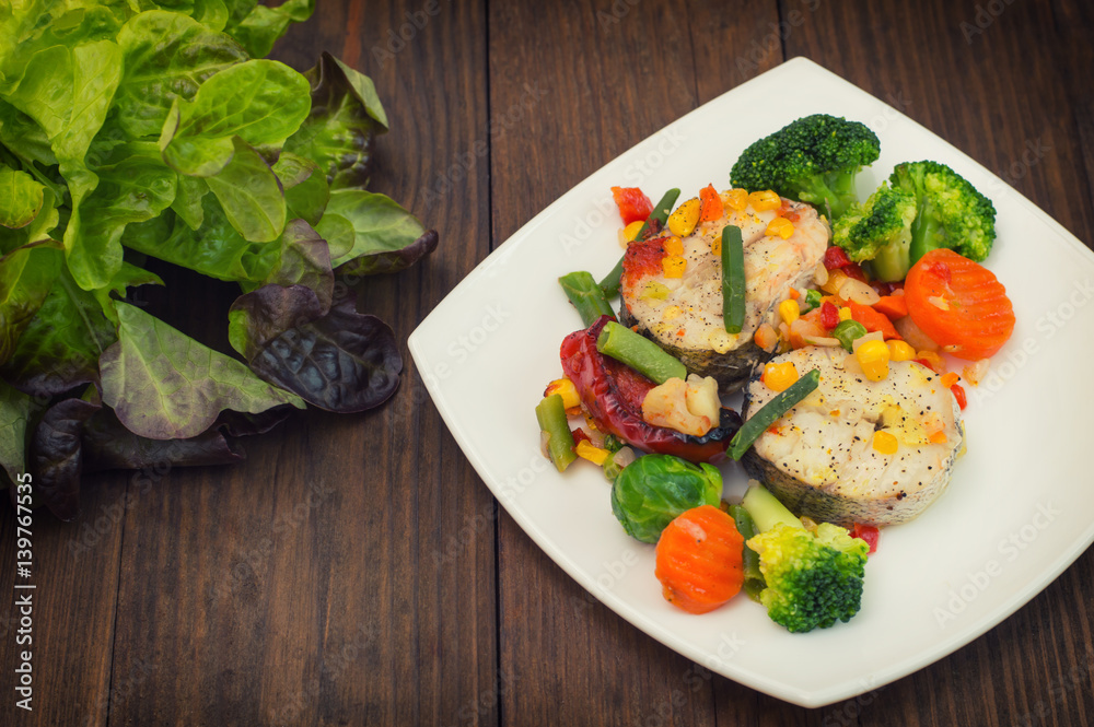 Fish fillet with mixed vegetables. Wooden background. Top view. Close-up Fish fillet with mixed vegetables. Wooden background. Top view. Close-up