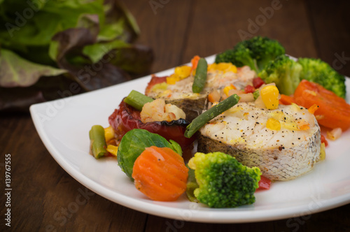 Fish fillet with mixed vegetables. Wooden background. Top view. Close-up