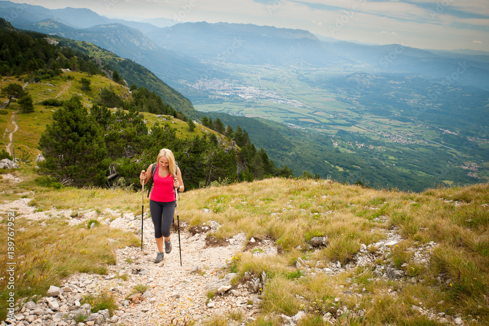 Trekking - woman hiking in mountains on a calm sumer day