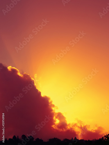 Cielo rosso al tramonto con raggi di sole che spuntano dietro ad una nuvola