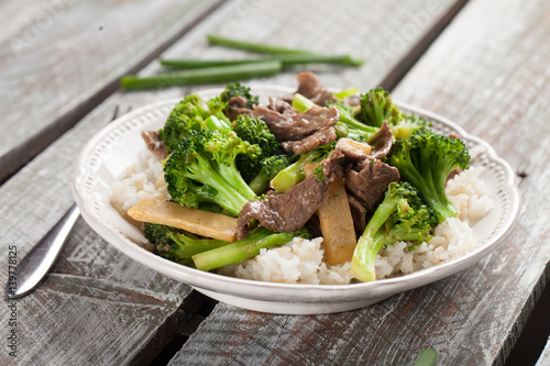 Beef N’ Broccoli Stir Fry on light weathered wood with green beans to side horizontal shot