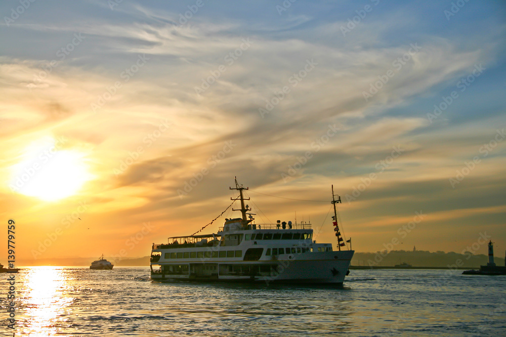 Silhouettes of turkish steamboat in Istanbul with seagulls at sunset