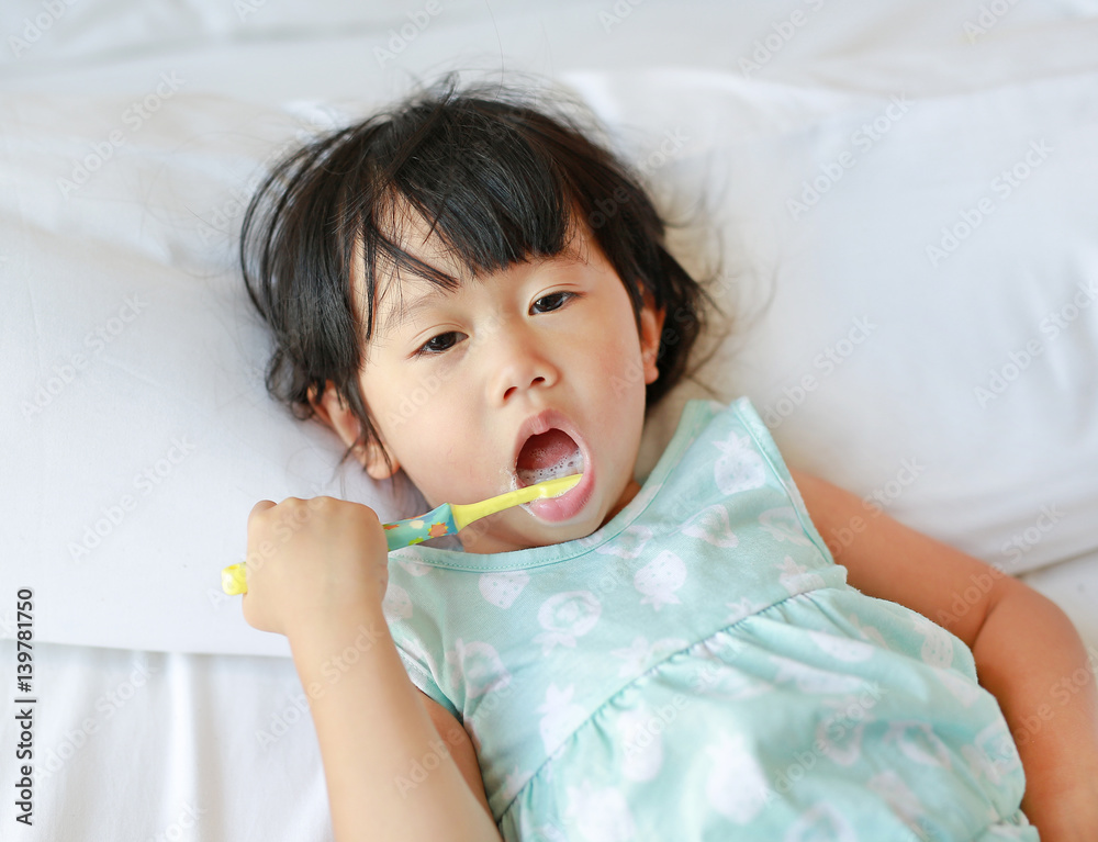 Kid girl brushing teeth on the bed at morning. Kid girl brushing teeth on the bed at morning.
