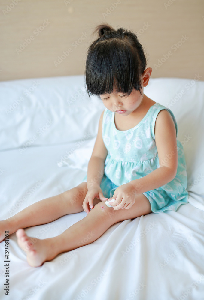 Close Up of child girl dressing wound on knee by self on the bed. Close Up of child girl dressing wound on knee by self on the bed.