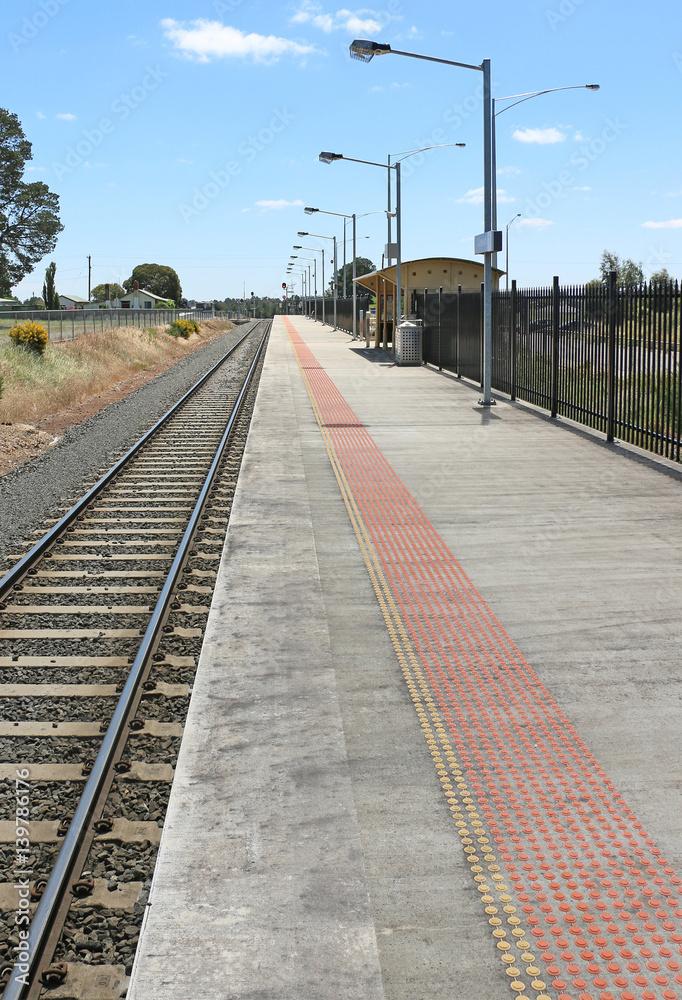 Fototapeta premium long train station platform alongside tracks