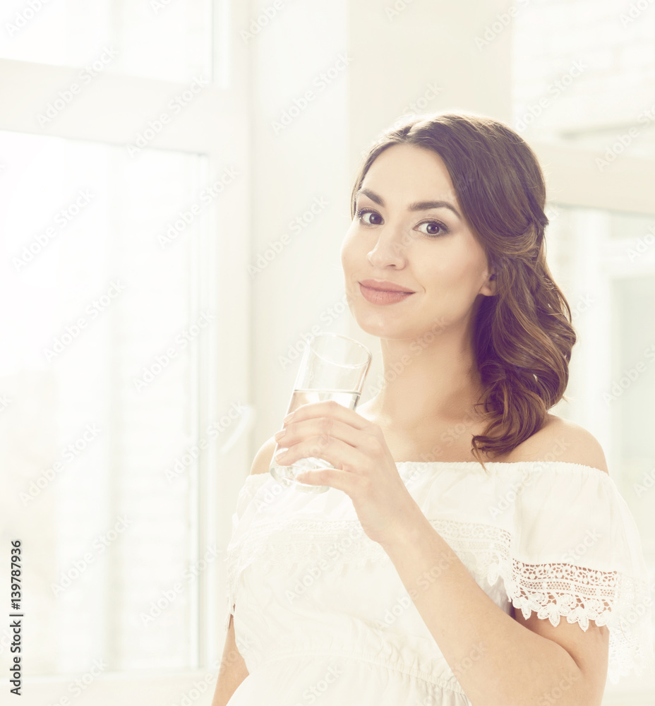 Beautiful, young woman with glass of water. Relaxing at home.