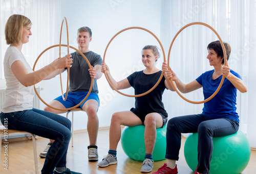 Sportgymnastik mit Holzreifen in der Physiotherapie auf Gymnastikbällen