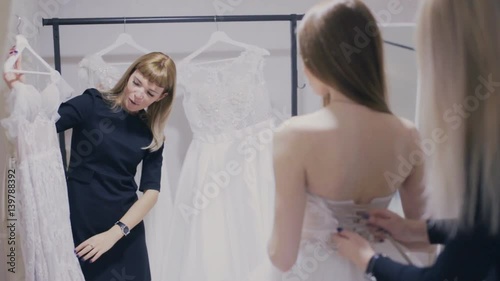 Consultant shows wedding gown in bridal shop