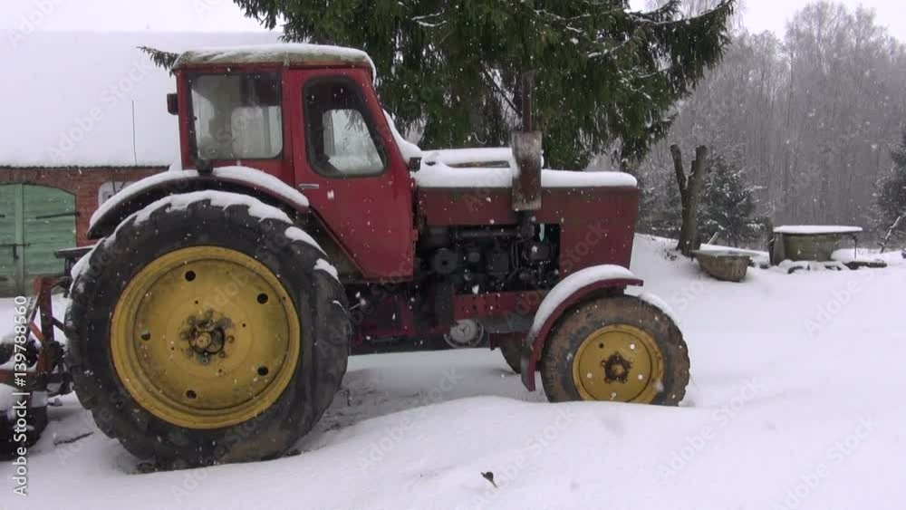 old retro soviet tractor in farm yard on snow and winter snowfall old retro soviet tractor in farm yard on snow and winter snowfall