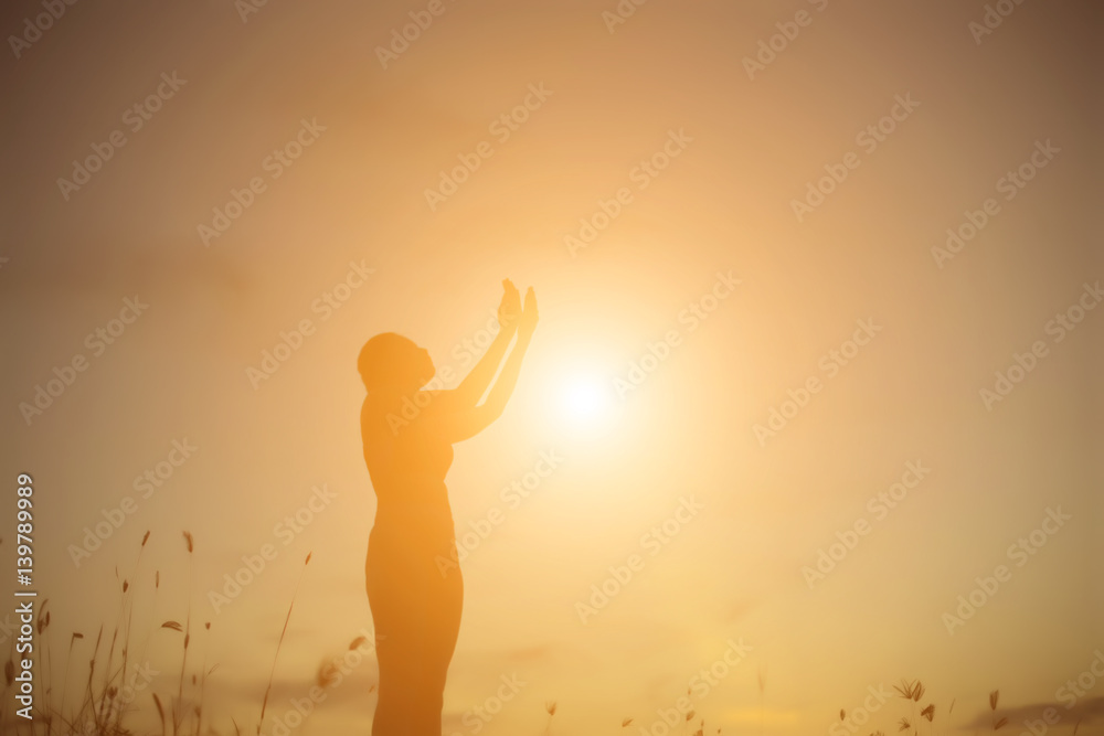 Silhouette of woman praying over beautiful sky background