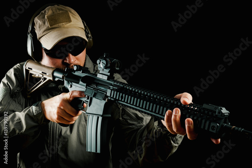 man in cap and jacket keeps assault rifle