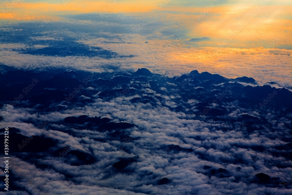 aerial sky with clouds at sunset or sunrise. above from airplane over the mountain.