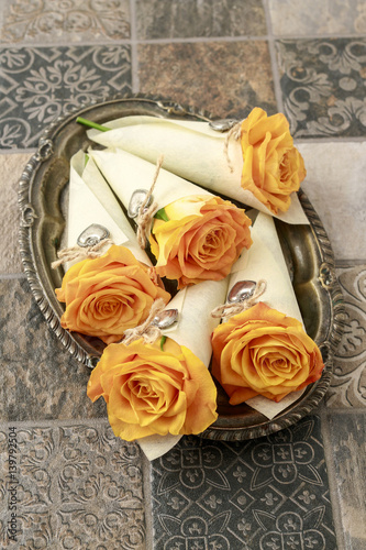 Orange roses in paper wrapping decorated with silver hearts.