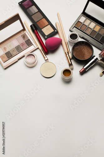 Flat lay of eyeshadow palettes,cosmetic brushes and lipstick. Space for text