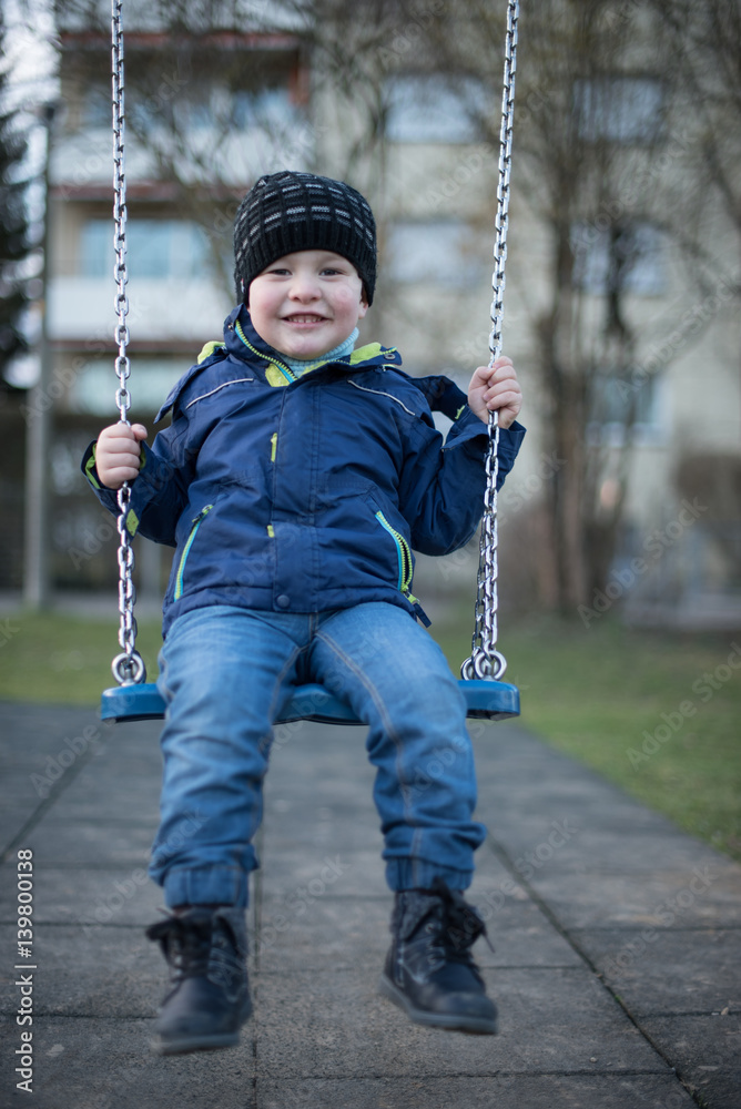 Little boy swinging on swing at children playground Little boy swinging on swing at children playground