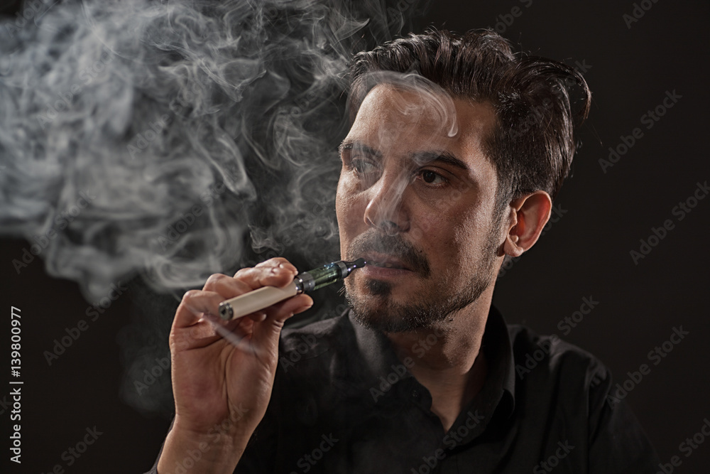 Fototapeta premium Portrait of man who is smoking electronic cigarette. 