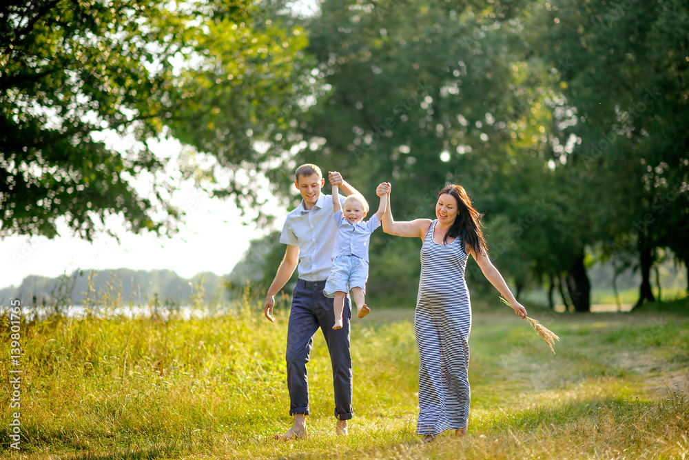 Fototapeta premium happy family walks in the wood on a sunset, play and have fun, bright evening light