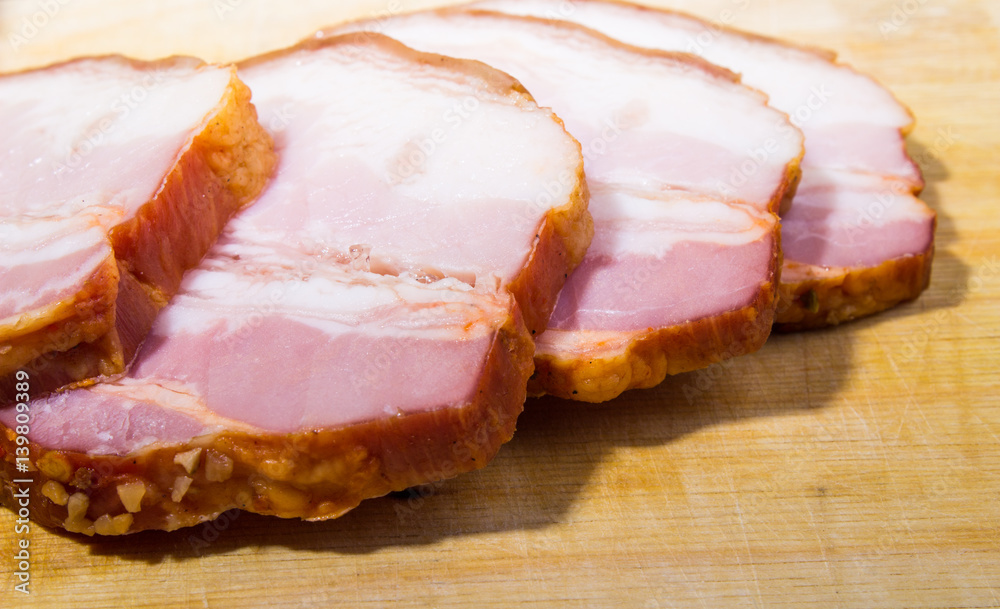 Raw smoked bacon slices on wooden board Raw smoked bacon slices on wooden board