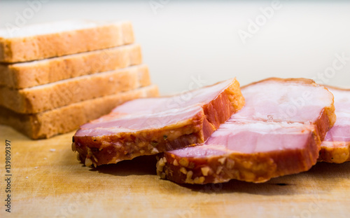 Raw smoked bacon slices with bread on wooden board