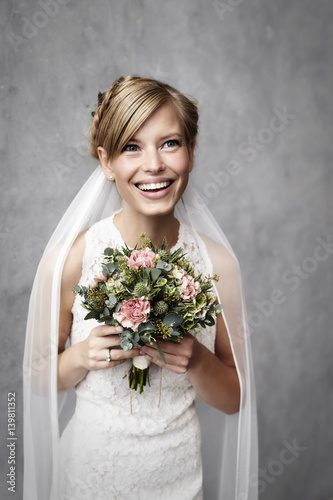 happy bride in wedding dress holding flowers