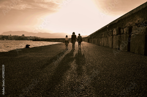 long shadows of people walking along the Venetian fortress of Koule at Heraklion port at sunset time.