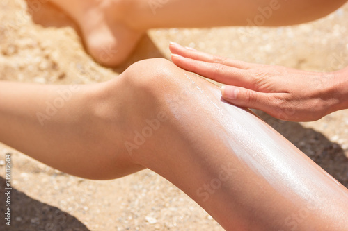 Girl applying sunscreen on leg. Hand of a young woman. Get tanned in June. Best protection for your skin.