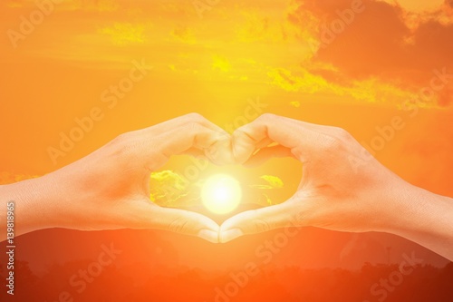 hand forming a heart shape with sunset light and copy space for add text