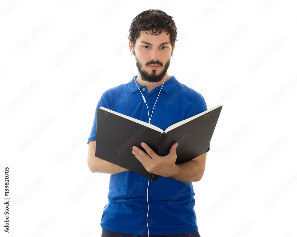 Young scholar checks notes in his notebook and hears music on the headset. Young man wearing blue polo shirt, white background, copy space. Young scholar checks notes in his notebook and hears music on the headset. Young man wearing blue polo shirt, white background, copy space.