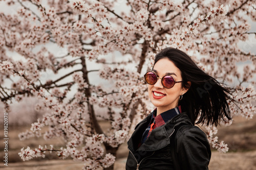 Attractive brunette girl near a almond tree with many flowers