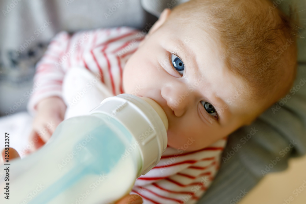 Mother feeding newborn baby daughter with milk in nursing bottle Mother feeding newborn baby daughter with milk in nursing bottle