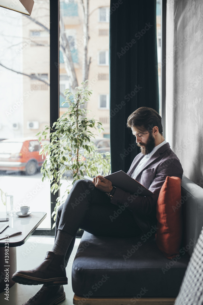 Handosme stylish Caucasian businessman writing in notebook at coffee shop. Handosme stylish Caucasian businessman writing in notebook at coffee shop.