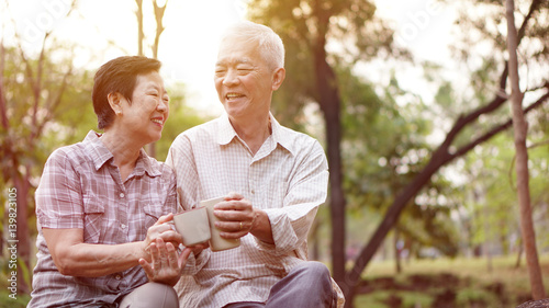 Healthy Asian senior couple drinking coffee in morning park together