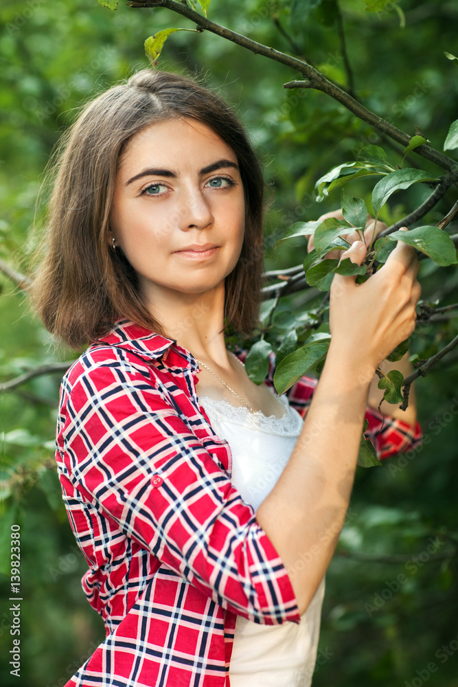 A young girl is sitting outdoors on the grass in a tree, brooding look, a summer day outdoors in the Park A young girl is sitting outdoors on the grass in a tree, brooding look, a summer day outdoors in the Park